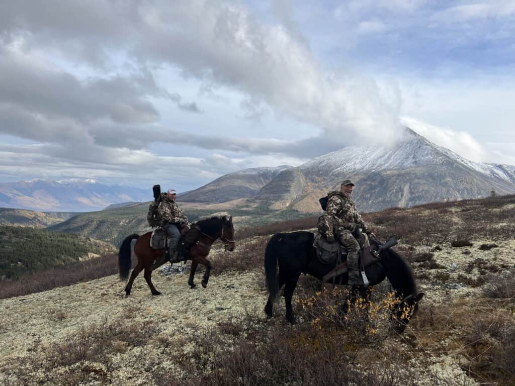 Scenic horseback riding adventure in mountains with hunters on horseback.